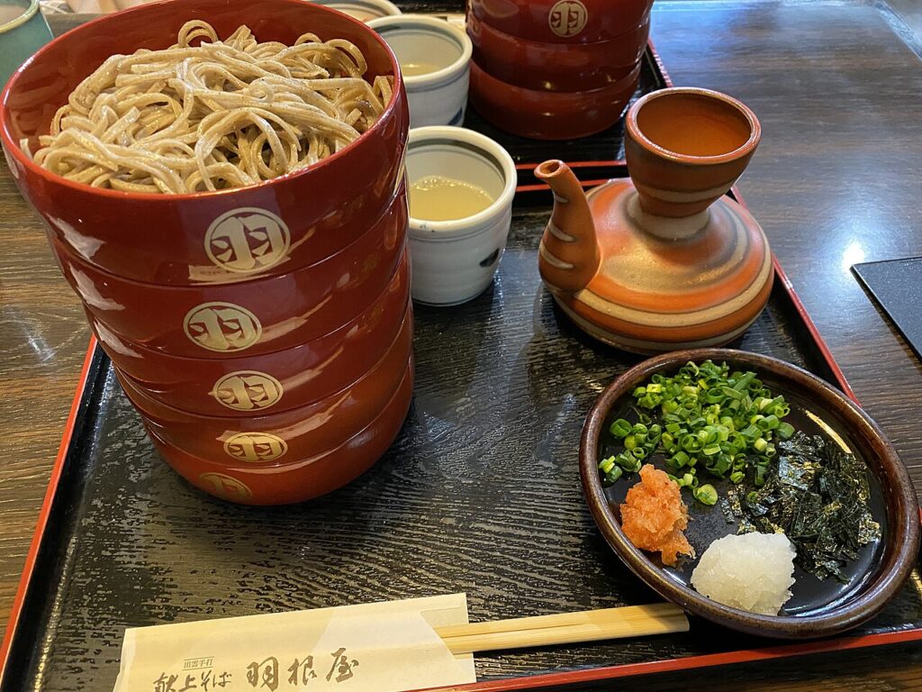 羽根屋で提供される割子の出雲そば。段の蕎麦に薬味が添えられる。
